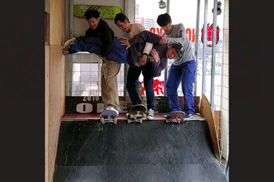 Three skaters with their friends on a mini ramp